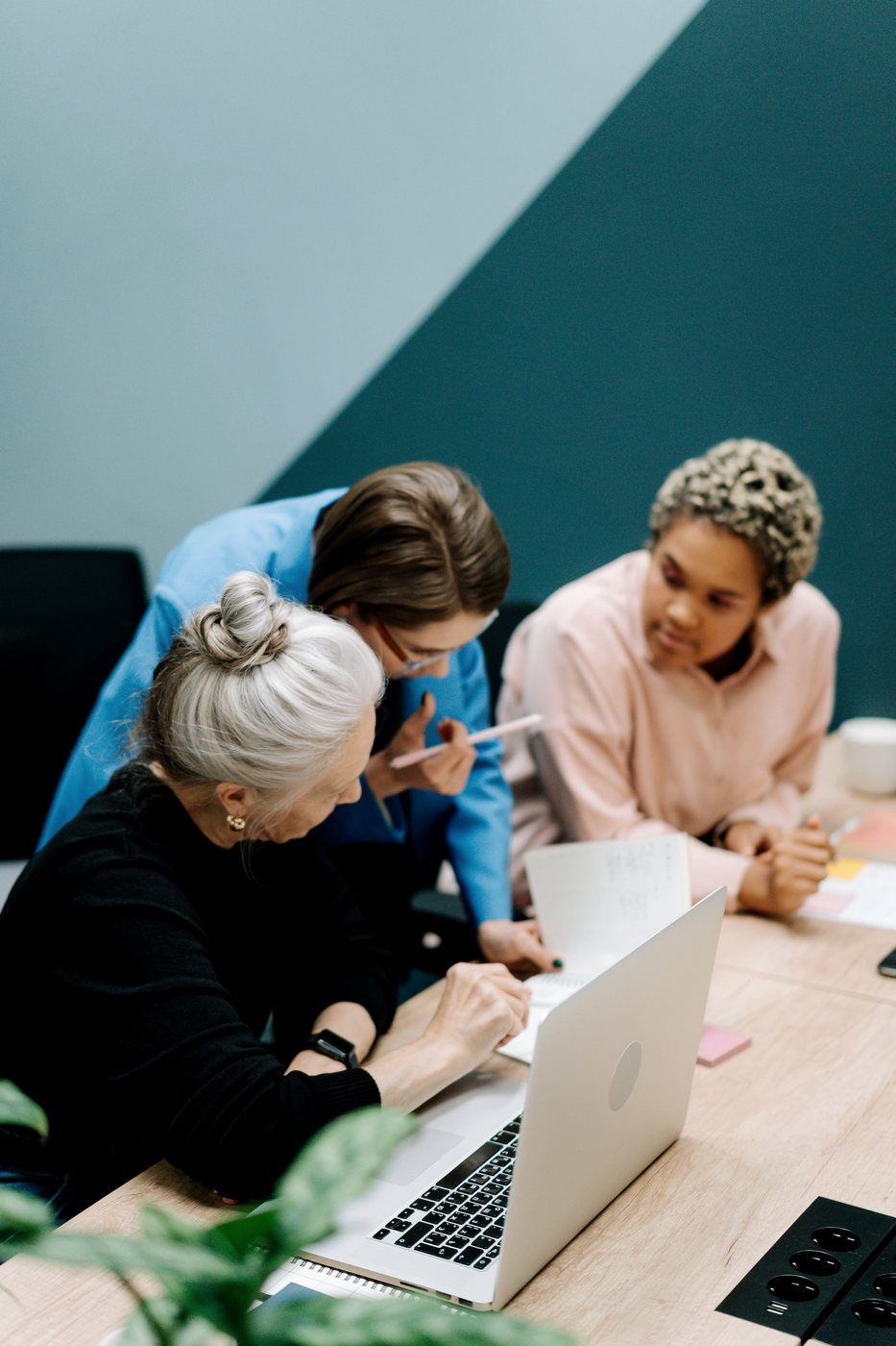 Three colleagues working through a problem at one laptop