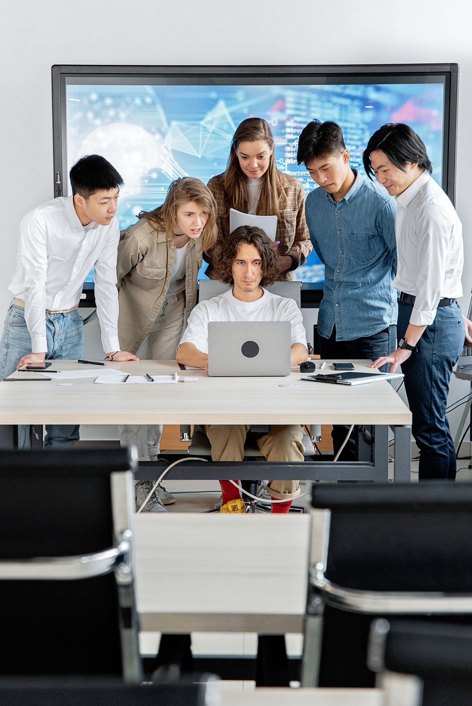A team gathered around one laptop, working through a problem together